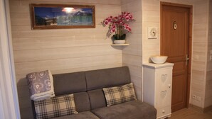 A room with a grey sofa, a white cabinet with heart-shaped cutouts, a wooden door, and a framed picture on the wall. - 200 m from the Saint Gervais les Bains cable car  (Saint-Gervais-les-Bains)