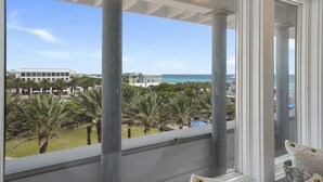 Uma varanda com vista para o oceano e palmeiras.