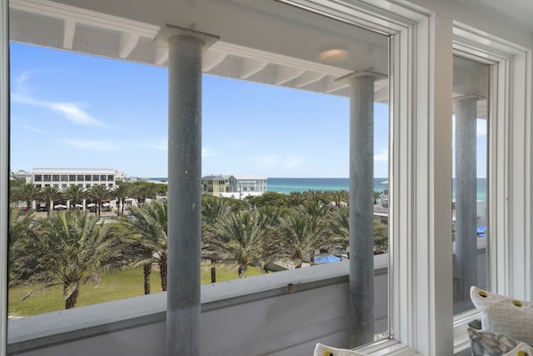 A balcony with a view of the ocean and palm trees.