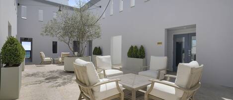 A courtyard with outdoor seating, a tree, and a building with multiple windows and doors.