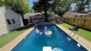A rectangular swimming pool with a clear blue surface, surrounded by a wooden fence and a grassy lawn. - Inground Pool, Arcade-Gameroom, 10 min to GR! (Wyoming)