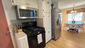 A kitchen with white cabinets, a stainless steel microwave, a gas stove, and a refrigerator. - Inground Pool, Arcade-Gameroom, 10 min to GR! (Wyoming)
