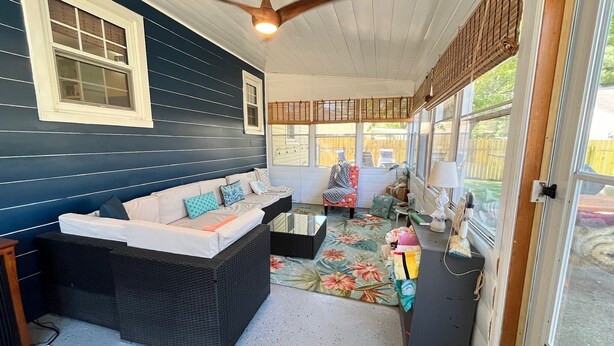 A covered porch with a dark blue wall, a white-framed window, a ceiling fan, a floral-patterned rug, and a wicker sofa with cushions. - Inground Pool, Arcade-Gameroom, 10 min to GR! (Wyoming)