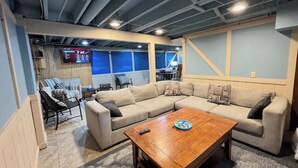A modern living room with a sectional sofa, a wooden coffee table, and a TV mounted on the wall. - Inground Pool, Arcade-Gameroom, 10 min to GR! (Wyoming)
