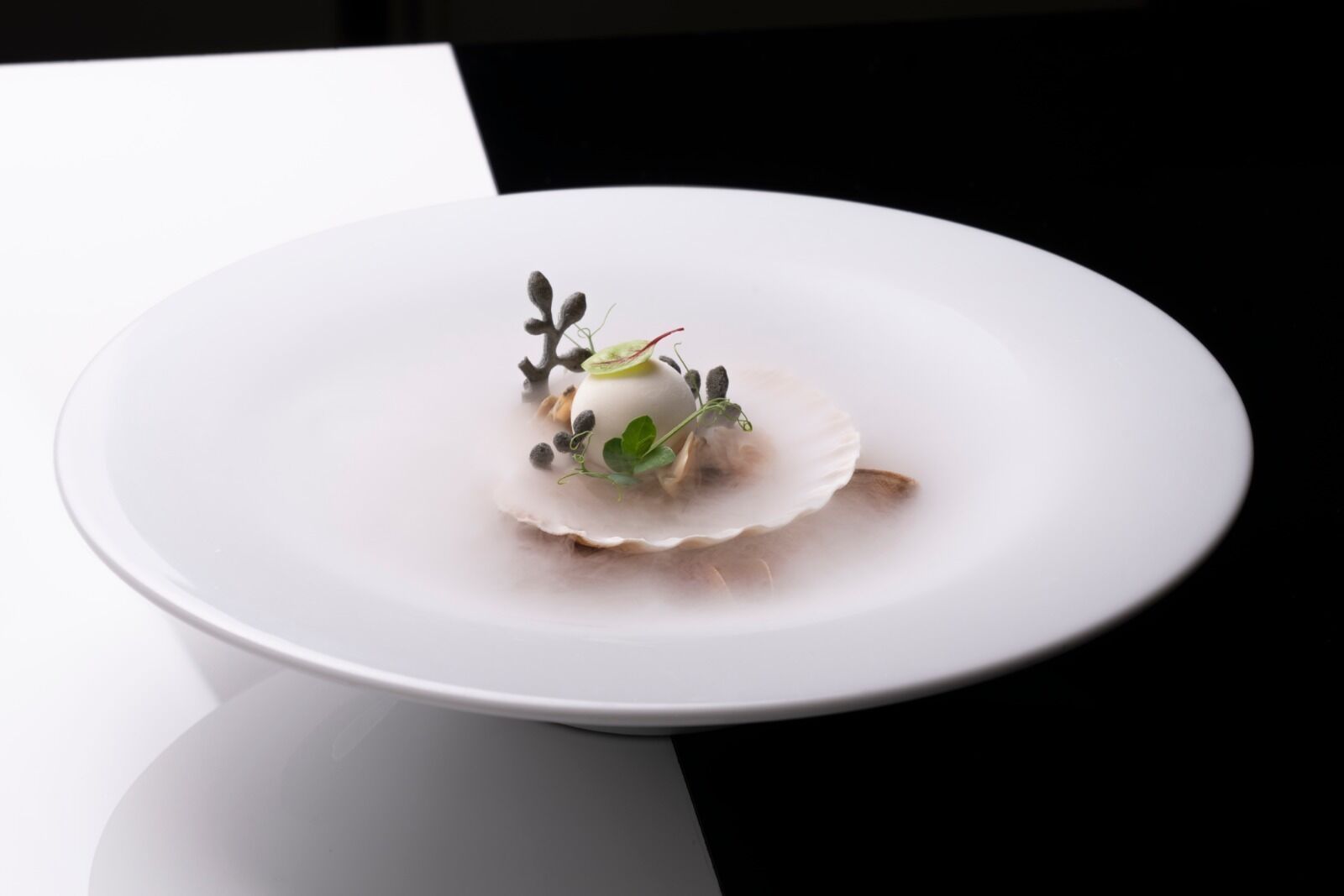 Un piatto bianco con un dessert su una superficie riflettente.