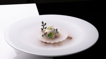 Un piatto bianco con un dessert su una superficie riflettente.