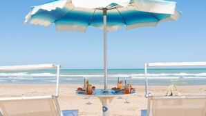 A beach umbrella with a table set for two, overlooking the ocean. - Rodi Resort (Rodi Garganico)