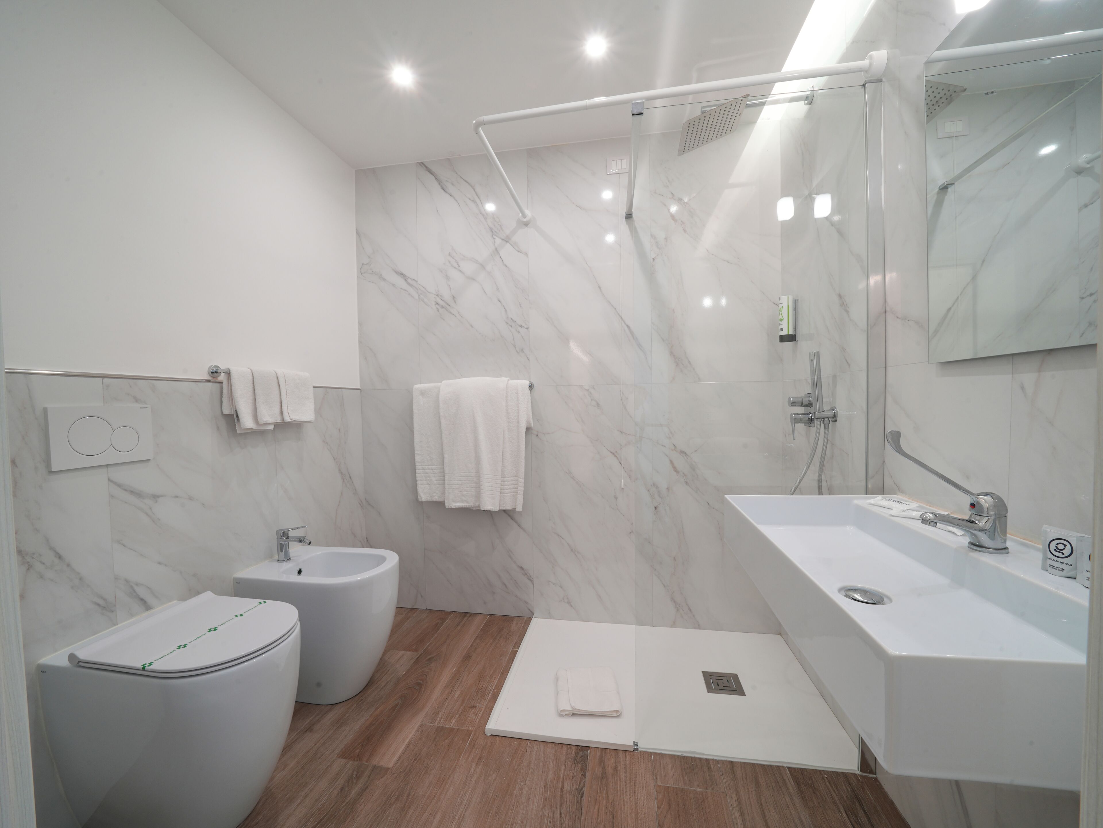A modern bathroom with a bidet, a large mirror, and a shower area.
