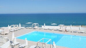 A pool area with lounge chairs and umbrellas, overlooking the sea. - Rodi Resort (Rodi Garganico)