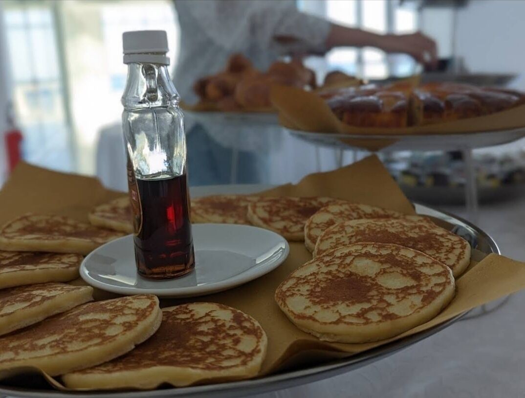 Un vassoio con pancakes, sciroppo e una bottiglia di sciroppo su un tavolo.