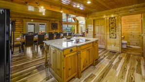 A wooden cabin interior with a kitchen, dining area, and bathroom. - Priceless Views, Game Room, Hot Tub, Firepit & Newly Remodeled! Free Tickets! (Gatlinburg)