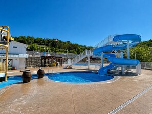 A pool area with a water slide, a lifeguard stand, and a covered seating area. - Fabulous 4BDR that sleeps 12 Cottage with Game Room in Stormy Point Village. (Branson)