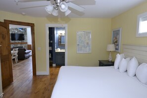 Une chambre d’hôtel équipée d’un lit, d’un bureau, d’une chaise, d’une télévision et d’un ventilateur de plafond.