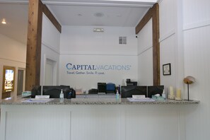 En reception med et skilt der siger 'Capital Vacations' og et skilt med teksten 'Medlemservice Check-In'.