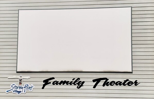 Un tableau blanc vierge, fixé au mur, avec des lignes horizontales et l’inscription « Théâtre familial » en bas.