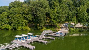 A dock with seating and a staircase leading to a platform, surrounded by dense forest. - Lake House with Golf Cart (Tullahoma)