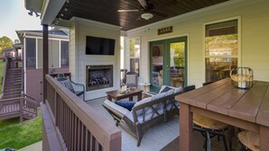A covered patio with a fireplace, outdoor seating, and a view of the backyard. - Lake House with Golf Cart (Tullahoma)