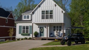 A two-story house with a front porch, a garage, and a golf cart parked in front. - Lake House with Golf Cart (Tullahoma)