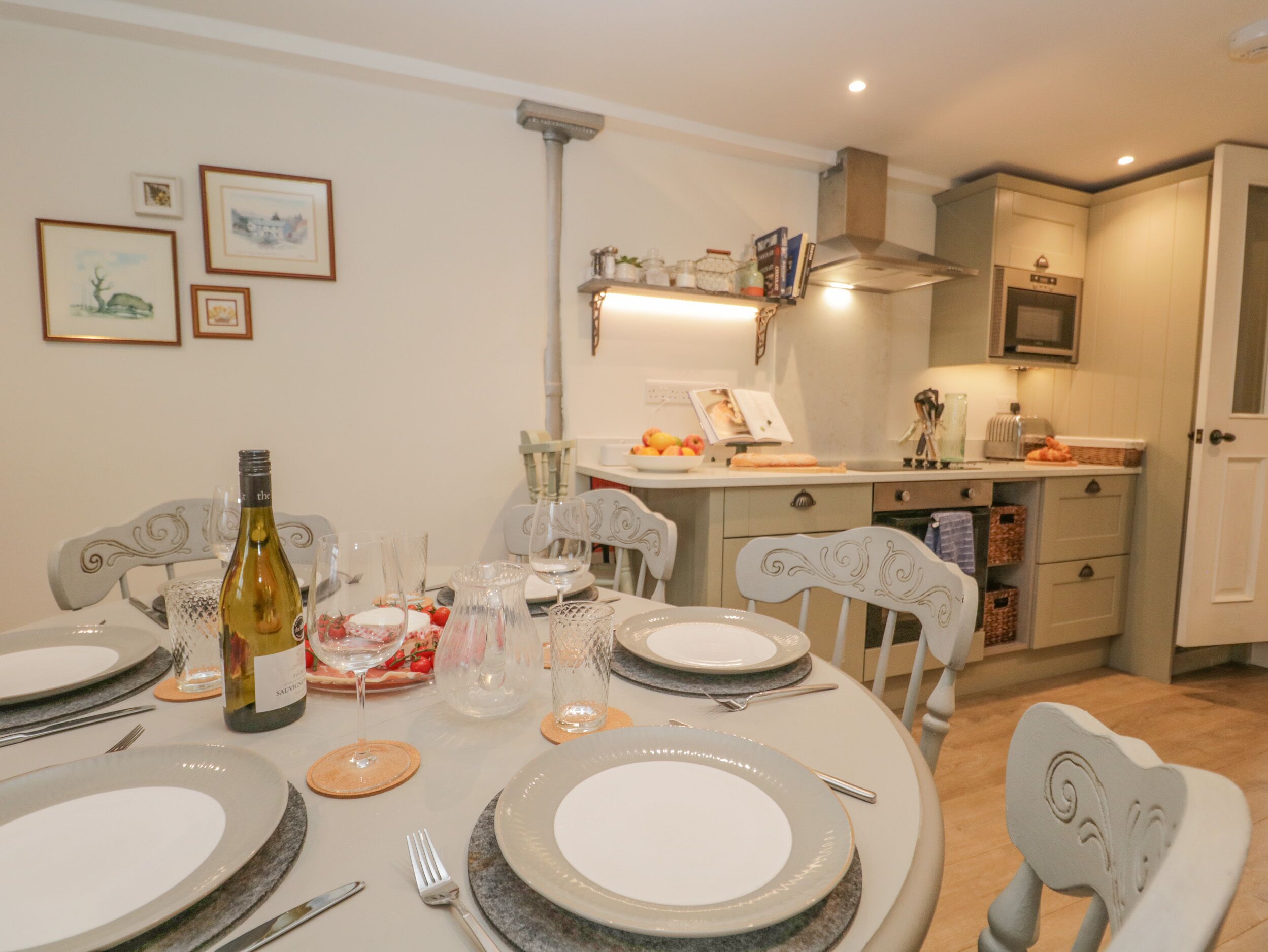 A dining area with a round table set for four, a bottle of wine, and various glassware.