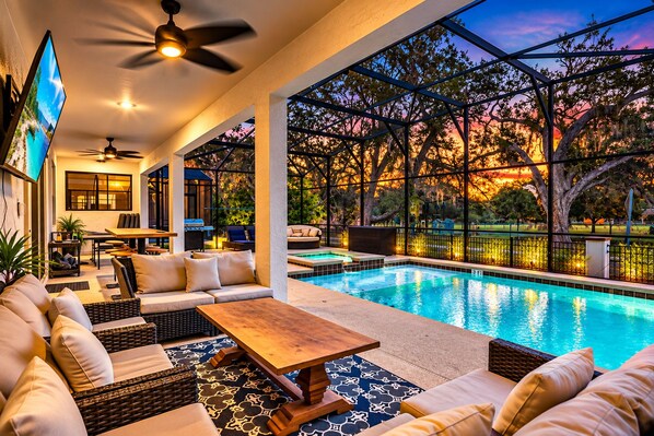 A poolside area with a sofa, table, and ceiling fan.