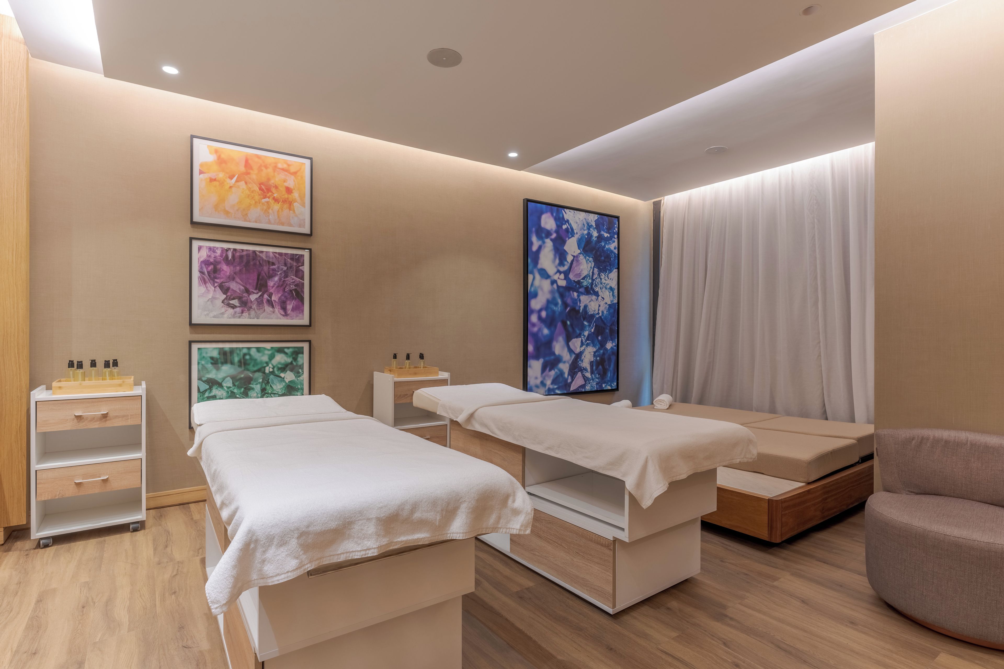 A room with two beds, a wooden cabinet, and a chair.