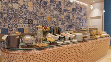 Un buffet proposant une variété de plats et un coin café, le tout installé sur un fond de carreaux bleus et blancs.