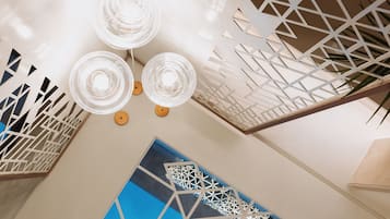A modern interior with geometric ceiling designs, a blue patterned wall, and a white decorative panel.