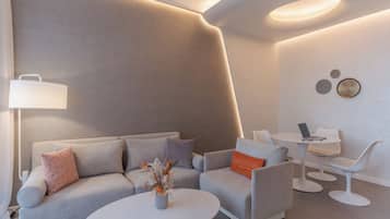 Un salon moderne comprenant un canapé, des fauteuils, une table basse, une table d’appoint et un bureau avec un ordinateur portable.