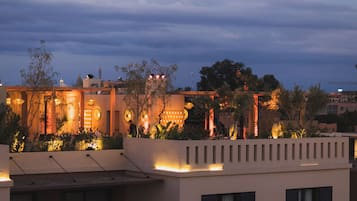 A modern building with a flat roof, large windows, and a balcony with plants.