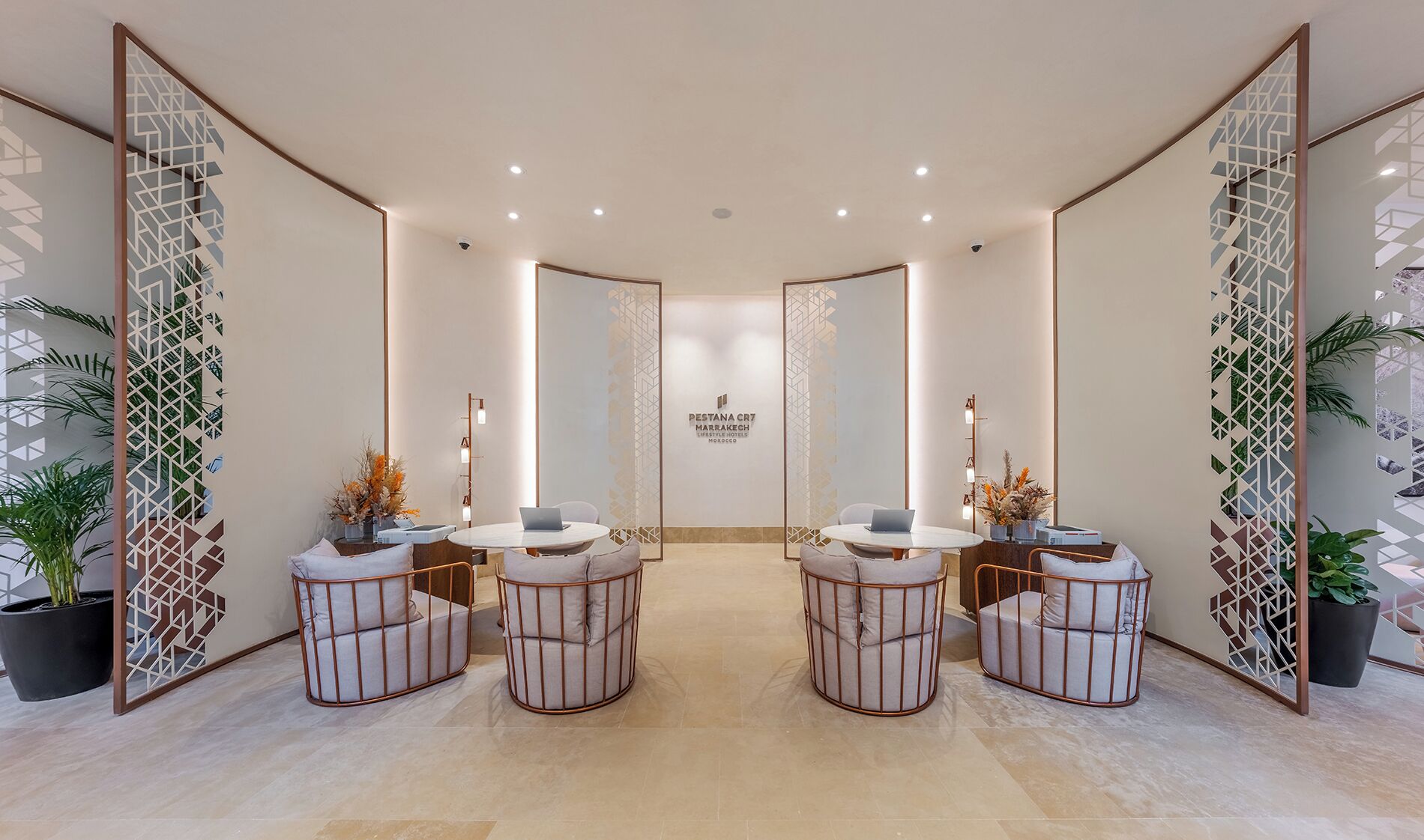 A modern, well-lit reception area with a central desk, four seating areas with round tables, and decorative panels on the walls.