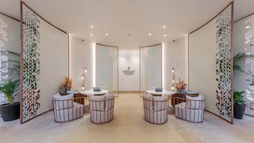 A modern, well-lit reception area with a central desk, four seating areas with round tables, and decorative panels on the walls.
