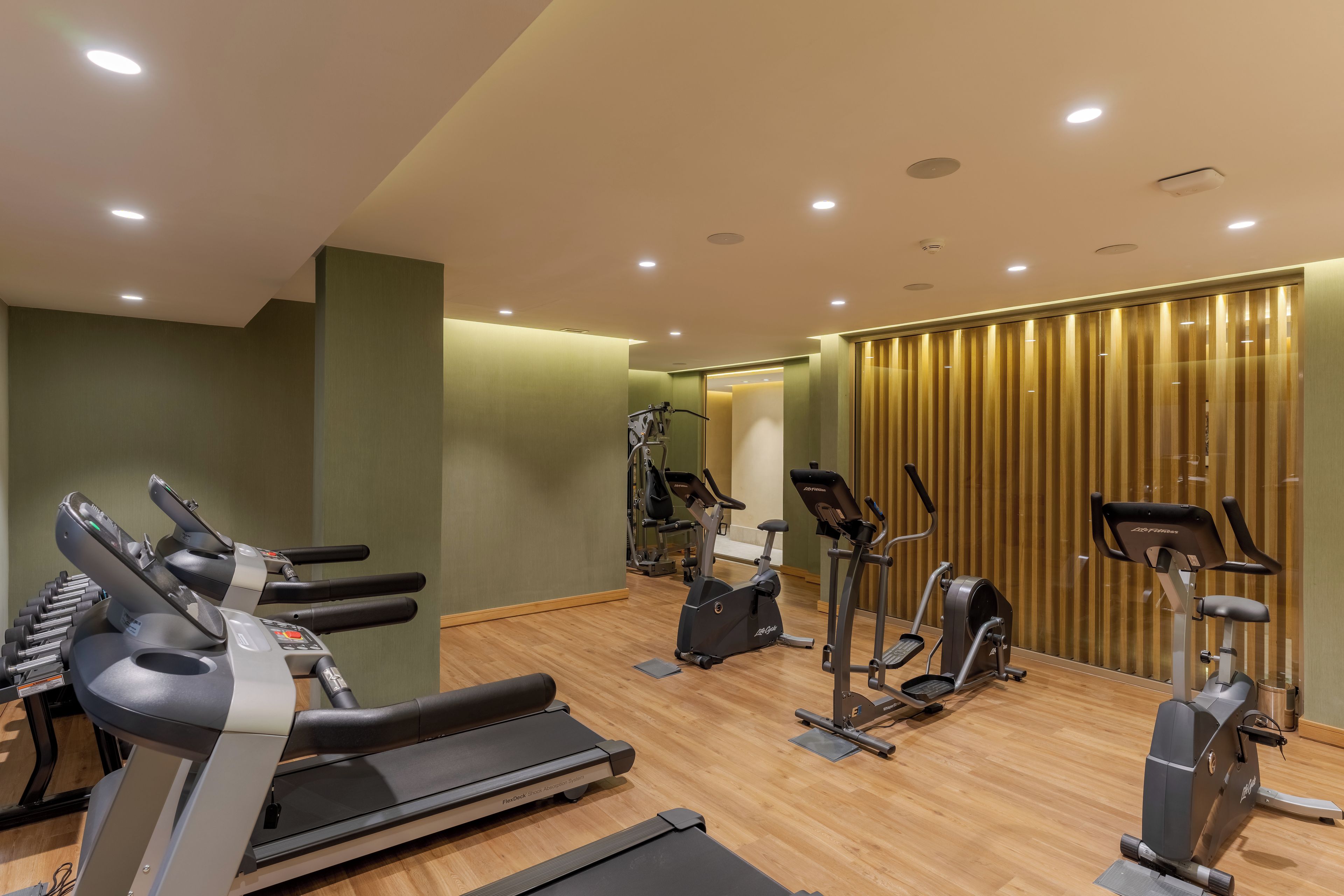 Une salle de sport équipée de divers appareils d’exercice, notamment des tapis de course, des vélos d’appartement et des appareils de musculation elliptique.