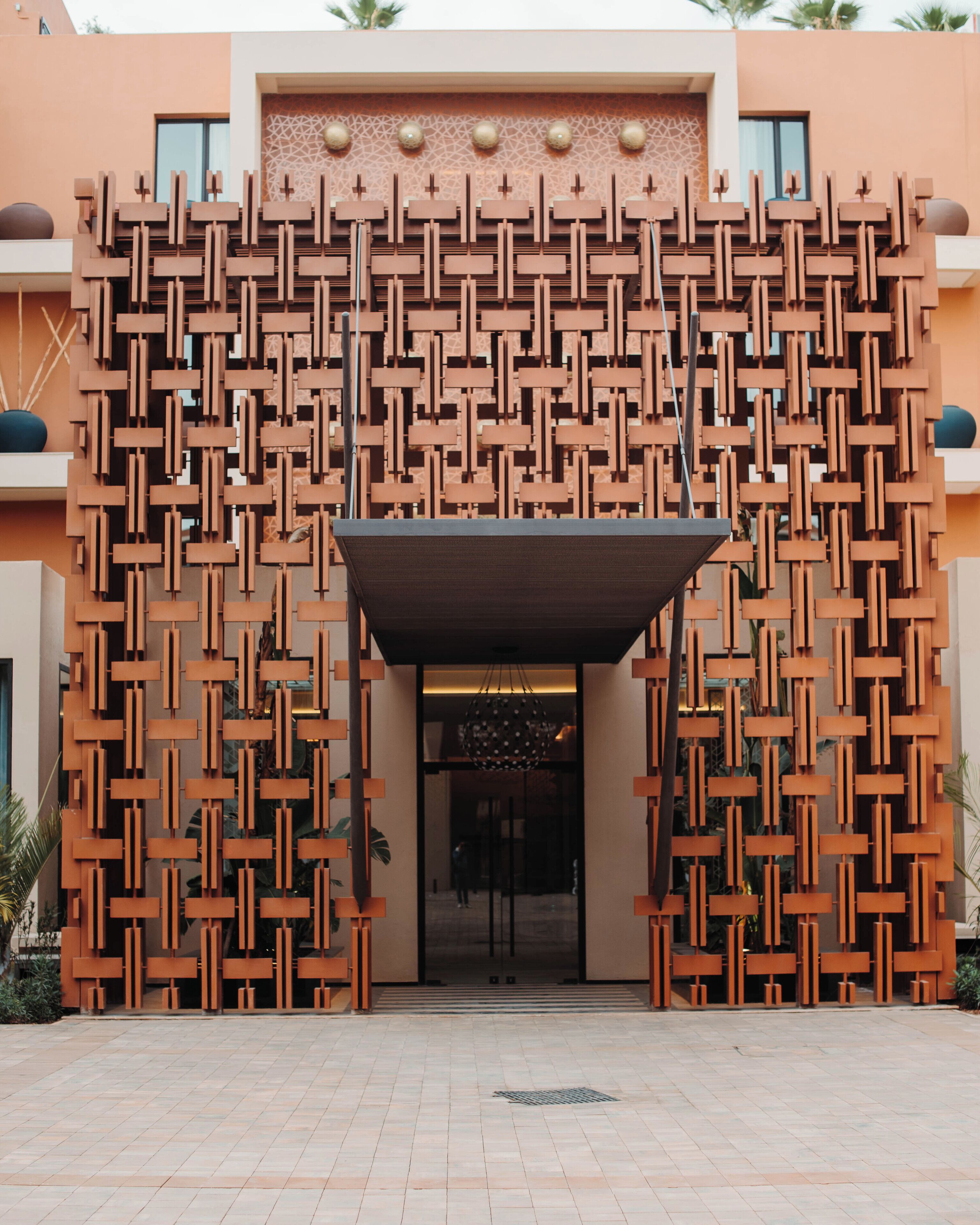 A modern building entrance with a geometric facade and a covered entrance area.