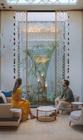 A modern interior with a large glass partition, a round wooden table, and a sofa.