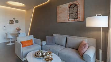 A modern living room with a grey sofa, a white coffee table with decorative items, a white floor lamp, and a wall-mounted artwork.