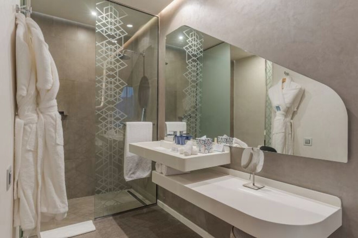 A modern bathroom with a glass shower enclosure, a white vanity, and a large mirror.