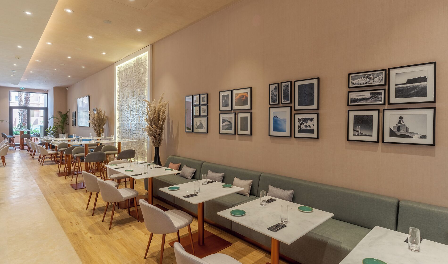 A modern restaurant with long tables, cushioned seating, and framed artwork on the walls.