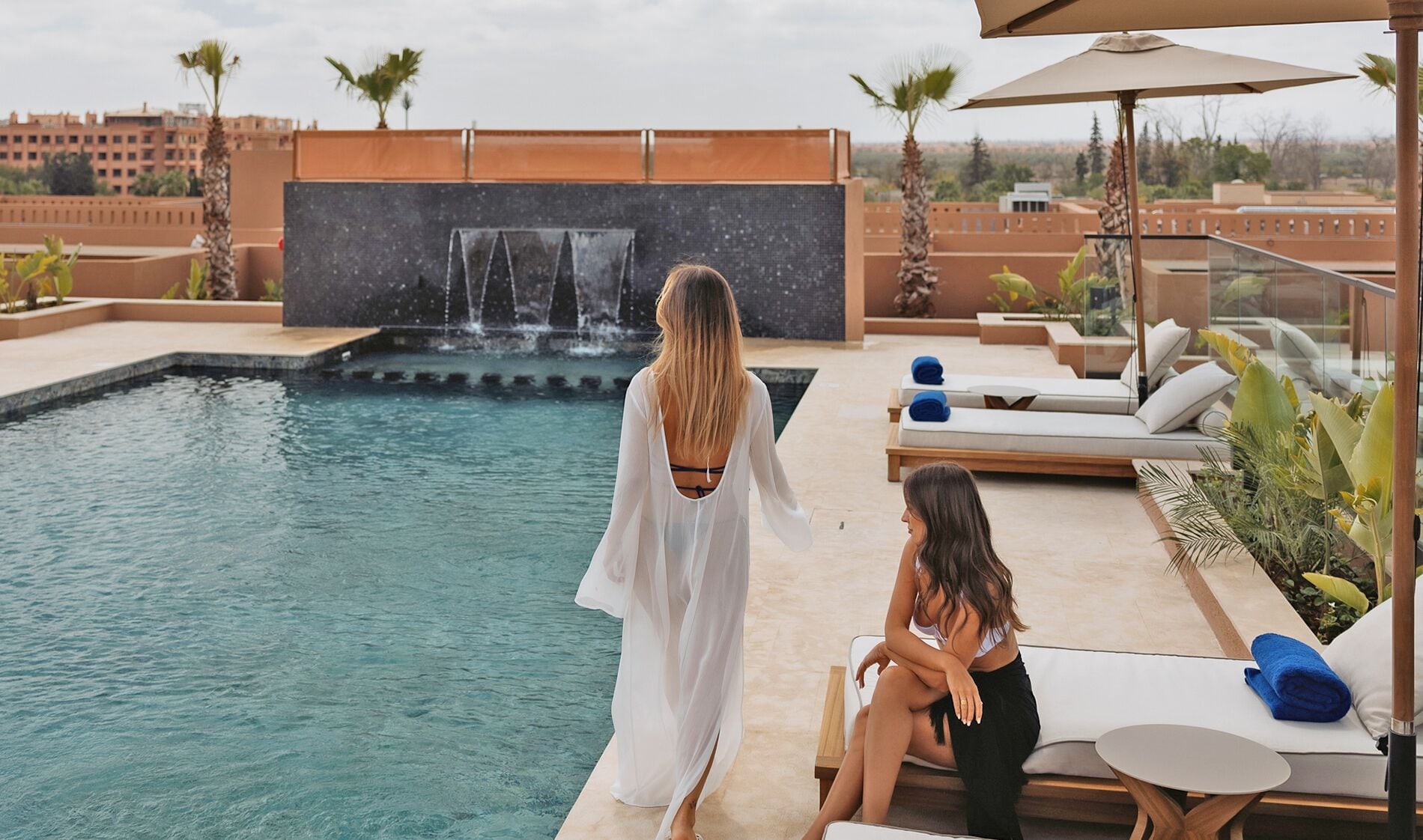 Ein Poolbereich mit Wasserfall, Liegestühlen und einer Sitzecke mit Tisch.