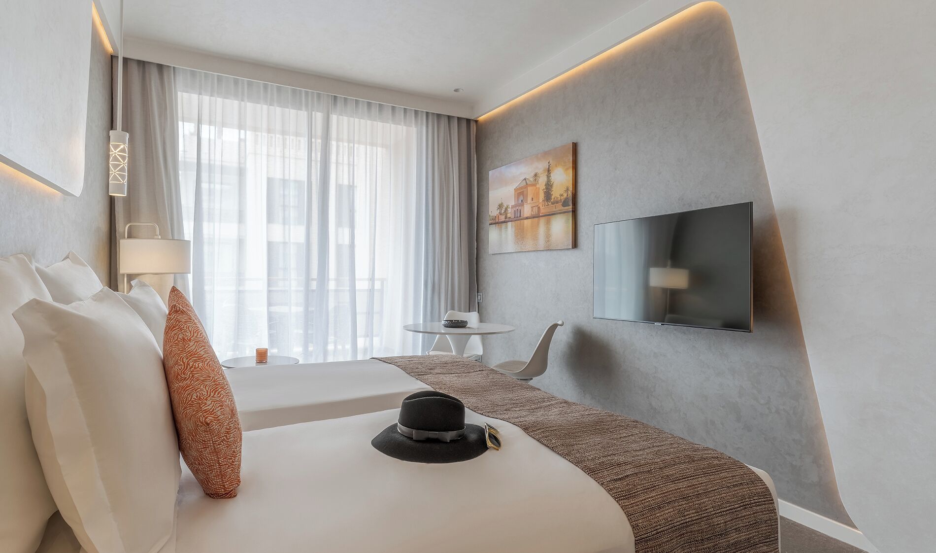 Een moderne hotelkamer met een bed, een bureau, een televisie en een schilderij aan de muur.