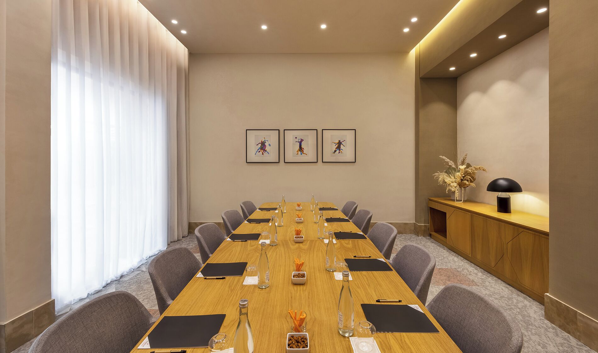 A conference room with a long table, chairs, and a wooden sideboard with a lamp.