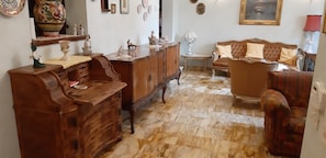 Ein wohnzimmer im Vintage-Stil mit einem Holzschrank, einer Couch und einem gemusterten Boden.