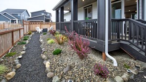 A residential building with a covered porch, a gravel pathway, and a wooden fence.