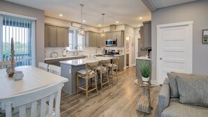 A modern kitchen with a central island, wooden chairs, and a dining table.