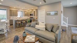 A spacious living room with a grey sofa, wooden coffee table, and a ceiling fan.