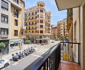 Straatbeeld met een rij geparkeerde scooters, een apotheek en een restaurant met terras.