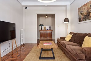 A living room with a television, wooden floor, brown sofa, and a lamp. - Always Easy I Larroca (San Sebastián/Donostia)