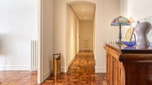A hallway with wooden flooring, a radiator, a brass lantern, a stained glass lamp, and a decorative vase. - Always Easy I Larroca (San Sebastián/Donostia)