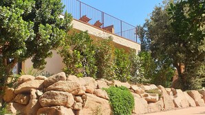 A stone retaining wall with a paved path, surrounded by greenery and a building with a red railing. - BERGERIE STONE HOUSE - HEATED PRIVATE SWIMMING POOL A Stella (Conca)