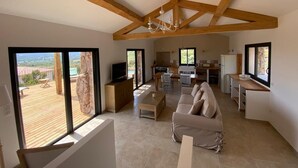 A spacious living area with a wooden ceiling, a sofa, a coffee table, and a kitchen in the background. - BERGERIE STONE HOUSE - HEATED PRIVATE SWIMMING POOL A Stella (Conca)