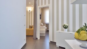 Een modern interieur met een gestreepte wand, een gele bank, een witte tafel en een schaal met citroenen.